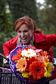 Woman riding bicycle holding flowers