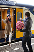 Man welcomes woman with flowers