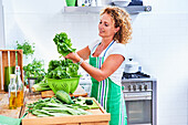 Woman cleaning green vegetables and lettuce in the kitchen