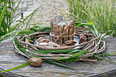 Windlicht umkleidet mit Pfahlmuschel in einem Kranz aus Clematis und Chinaschilf (Miscanthus)