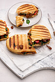 Vegan grilled panini sandwich with soya shreds, spinach and peppers