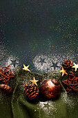 Cones, Christmas baubles, stars and icing sugar decoration on a green background