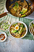 Aubergine and peanut stir fry with egg, noodles and pak choi