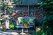 Sitzbereich im Garten mit Steintisch und Holzbank vor Backsteinwand