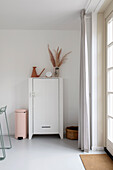 White chest of drawers with dried flower decoration and geometric vase in the minimalist living room