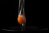 Raw egg falls into a bowl against a black background