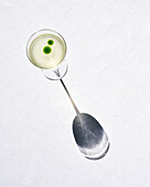 Gin cocktail in a glass on a light-coloured background with shadows