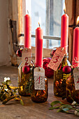 Advent candles in glass bottles decorated with red baubles and fir branches