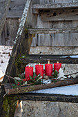 Adventsdekoration mit roten Kerzen auf einer alten Holztreppe