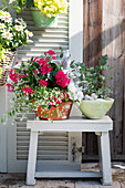 Blumenarrangement mit roten Pentas und Eukalyptus auf Holzhocker