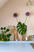 Decorative kitchen corner with monstera leaf in vase and chopping boards