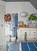 Bedroom with light-coloured chest of drawers, blue textiles and sloping ceiling