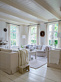 Living room with light-coloured sofas and white wooden beamed ceiling