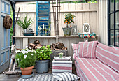 Terrace with striped sofa, potted plants and rustic wooden elements