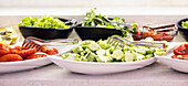 Fresh vegetables, cucumbers, tomatoes and salad in bowls on buffet in the restaurant