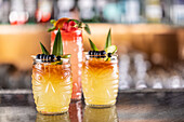 Mai tai cocktails in Hawaiian glasses, garnished with pineapple, blueberries and strawberries