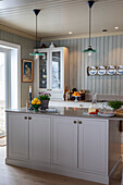 Kitchen island with grey cabinets and green pendant lights in country house kitchen