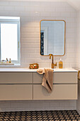 Modern bathroom with golden fittings and patterned tiled floor