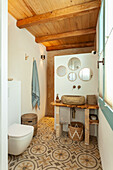 Bathroom with rustic wooden washbasin, wooden ceiling and patterned tiles