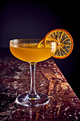 Orange-coloured cocktail with dried orange slice