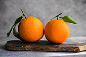 Oranges with leaves on wooden board