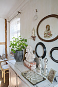 Sideboard in shabby chic look, bust, picture frame and green plant