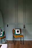 Mustard yellow velvet chair in front of pastel green built-in wardrobe in bedroom