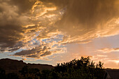Virga or evaporating rain falling from colorful clouds at sunset near Moab, Utah.