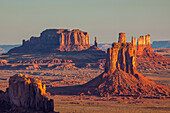Sunrise in Monument Valley Navajo Tribal Park in Arizona with the East Mitten at center & the Utah monuments behind. Brigham's Tomb is at left with the Bear & Rabbit and the Stagecoach at right.