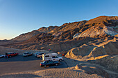 Touristen betrachten die bunten erodierten Badlands der Artist's Palette bei Sonnenuntergang im Death Valley National Park in Kalifornien