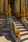 Yaksha guardian statues at the Phra Mondhop in the Grand Palace grounds in Bangkok, Thailand. A yaksha or yak is a giant guardian spirit in Thai lore. A golden five-head naga, or water deity is in front.