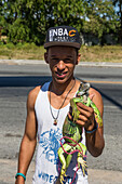 A young man in a ball cap selling an iguana by the roadside in Bani, Dominican Republic.