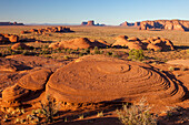 Eroded sandstone in Mystery Valley in the Monument Valley Navajo Tribal Park in Arizona. The Utah monuments are behind.
