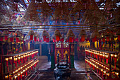 A worshipper enters the Man Mo Temple, a Buddhist temple in Hong Kong, China. Incense coils hang overhead.