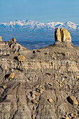 Angel Peak Scenic Area bei Bloomfield, New Mexico. Die Kutz Canyon Badlands mit den schneebedeckten San Juan Mountains im Hintergrund