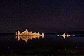 Tufa formations and stars reflected in Mono Lake in California at night.