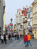 Menschen spazieren auf einer Straße mit klassischer Architektur in der historischen Altstadt von Vilnius, Litauen. Eine UNESCO-Welterbestätte