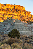 Sonnenuntergang an den Sandsteinklippen im nordwestlichen New Mexico, USA. Im Vordergrund ist ein erodierter Schieferhügel