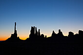 The Totem Pole and the Yei Bi Chei in silhouette before dawn in the Monument Valley Navajo Tribal Park in Arizona.