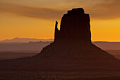 Colorful sunrise sky behind the East Mitten Butte in the Monument Valley Navajo Tribal Park in Arizona.