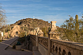 Gewölbter Durchgang durch die Schutzmauer um die Mission San Xavier del Bac, Tucson Arizona. Der Grottenhügel mit seinem weißen Kreuz liegt dahinter