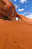 Coyote tracks in the sand in front of the Ear of the Wind Arch in the Monument Valley Navajo Tribal Park in Arizona.