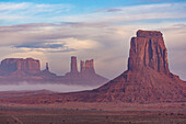 Nebliger Morgenblick aus dem Nordfenster auf die Utah-Monumente im Monument Valley Navajo Tribal Park in Arizona. L-R: Castle Butte, Bear and Rabbit, Stagecoach, East Mitten Butte