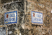 Straßenschilder an der Ecke der Calle El Conde und der Calle Las Damas in der Kolonialstadt Santo Domingo, Dominikanische Republik. Bei diesem alten Kolonialgebäude soll es sich um das ehemalige Wohnhaus von Henan Cortez, dem Eroberer von Mexiko, handeln. Ein UNESCO-Weltkulturerbe