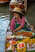 A Thai woman preparing food on her boat in the Damnoen Saduak Floating Market in Thailand.