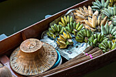 Ein traditioneller thailändischer Hut und Bananen zum Verkauf auf einem Boot auf dem schwimmenden Markt von Damnoen Saduak in Thailand