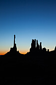 The Totem Pole and the Yei Bi Chei in silhouette before dawn in the Monument Valley Navajo Tribal Park in Arizona.