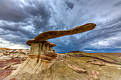 The King of Wings, a very fragile sandstone hoodoo in the badlands of the San Juan Basin in New Mexico, with storm clouds behind.