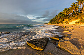 Waves breaking on the rocks at sunrise on a beach near Barahona, Dominican Republic. A slow shutter speed gives the water a blurred look.