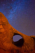 The Milky Way over Moccasin Arch at night in the Monument Valley Navajo Tribal Park in Arizona.